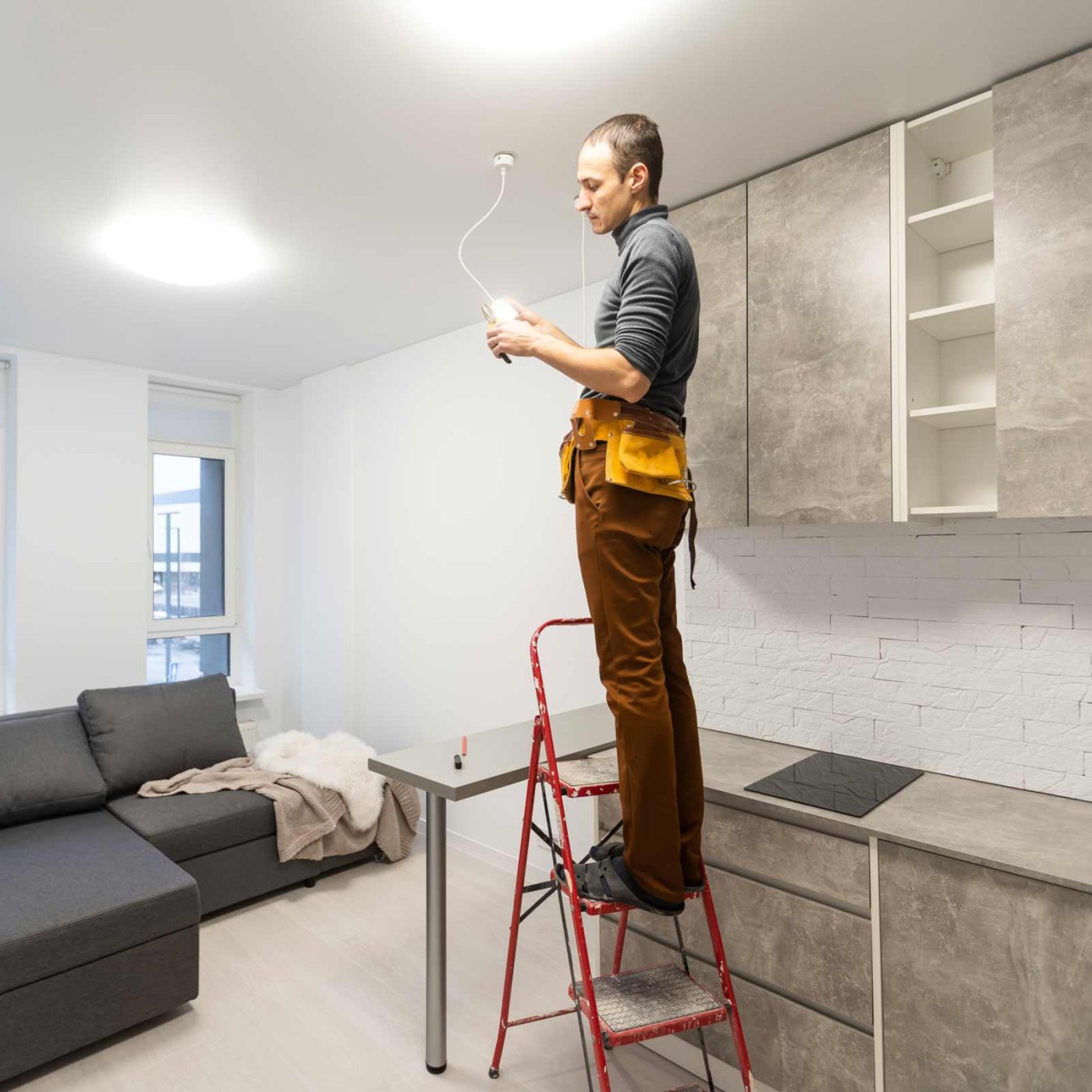 NCCS Group - An electrical engineer installing a ceiling light in the kitchen.