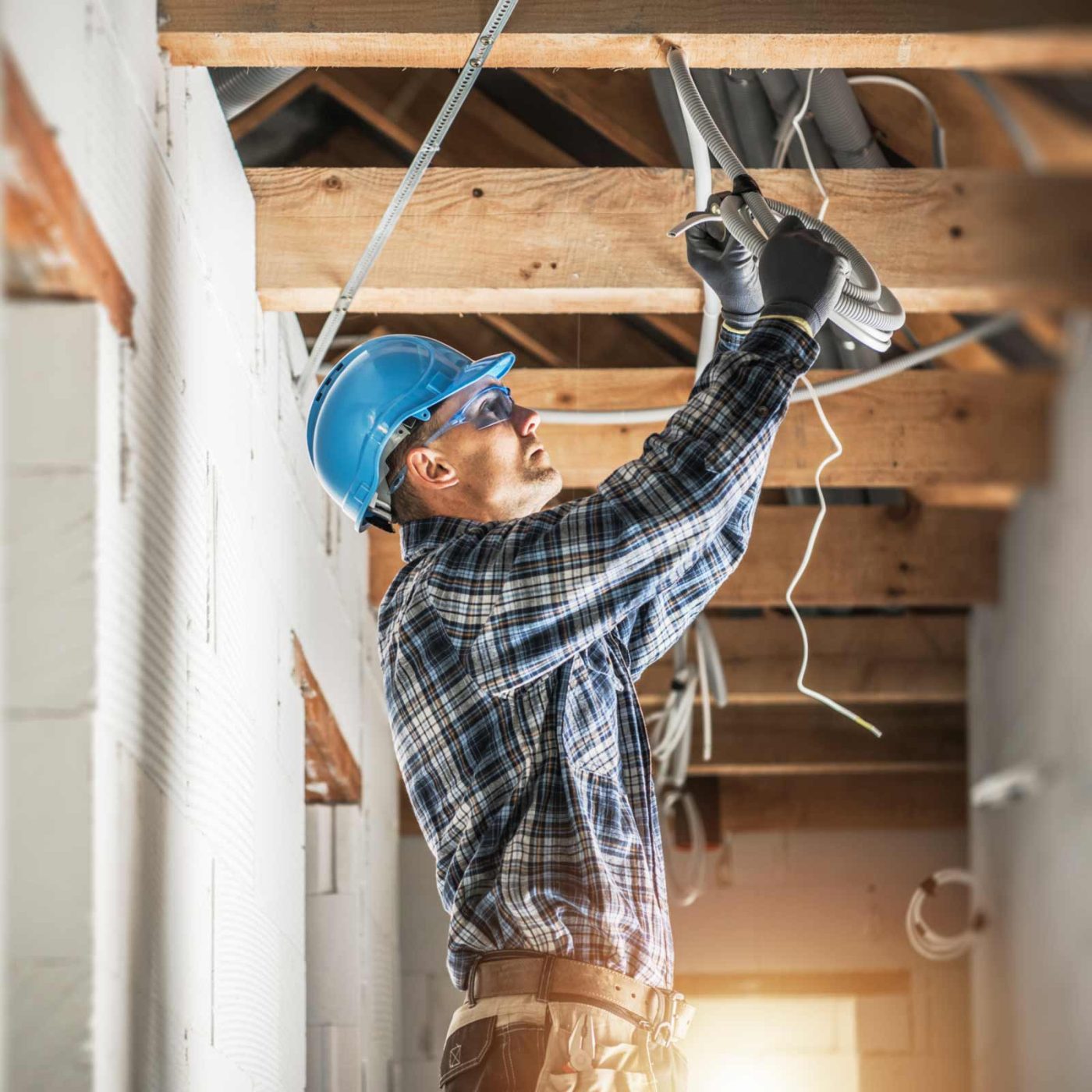 NCCS Group - Engineer wiring cables into an unfinished ceiling.
