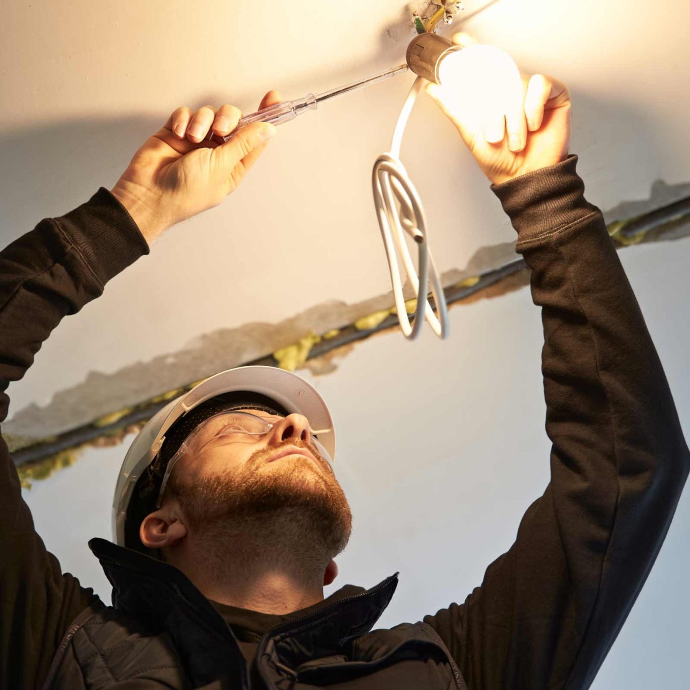 NCCS Group - Engineer using screwdriver to fix light fixture in ceiling.