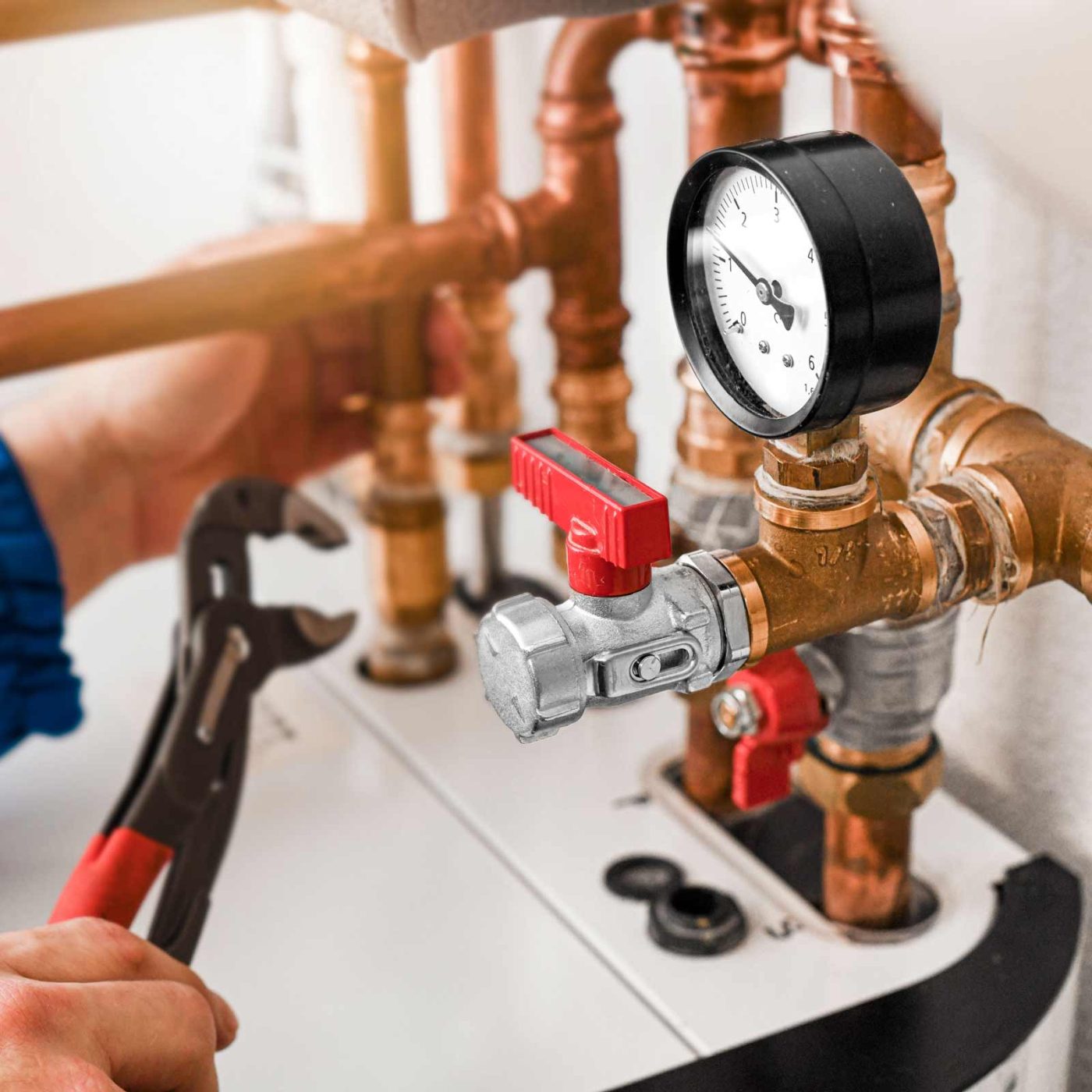 NCCS Group - Heating Commercial - Engineer fixing copper pipes and pressure gauge with spanner.