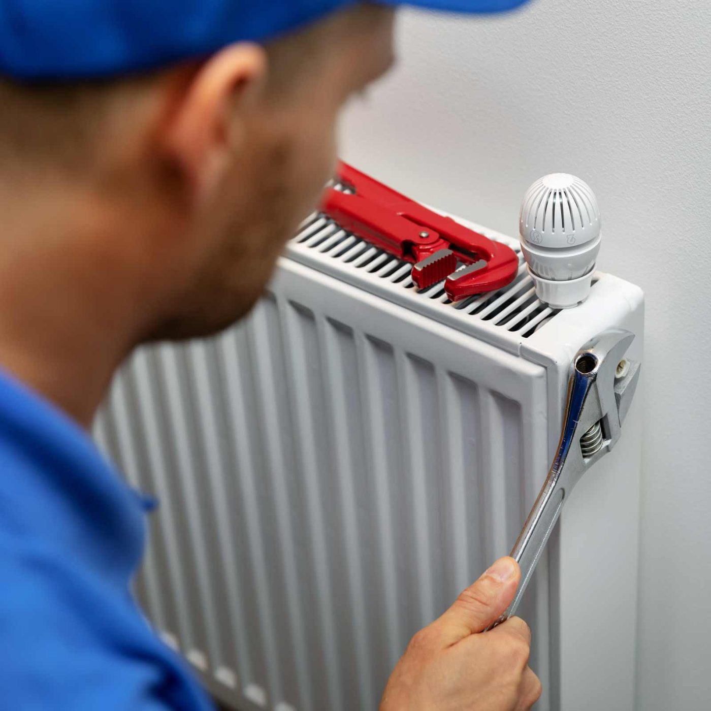 NCCS Group - Heating Domestic - Engineer adjusting a radiator in a room.