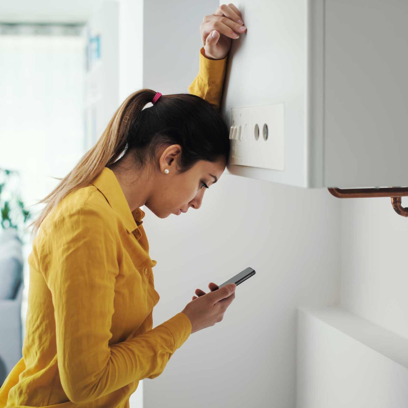 NCCS Group - A woman on mobile phone leaning against heating boiler.