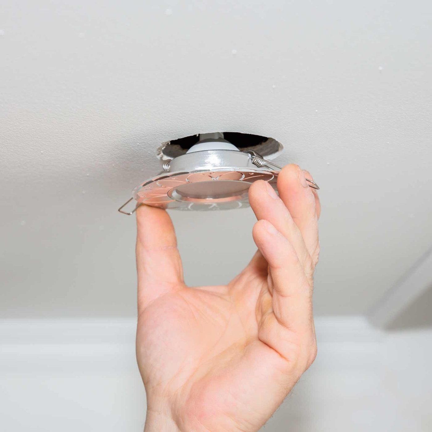 NCCS Group - A person installing a ceiling track light.